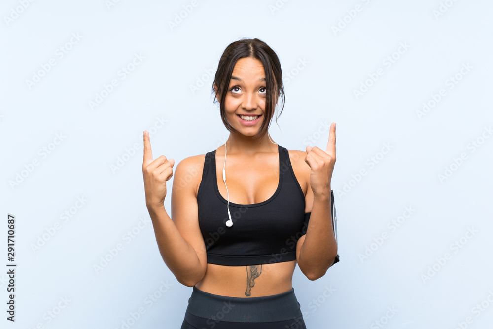 Young sport girl over isolated blue background pointing up a great idea Young sport girl over isolated blue background pointing up a great idea