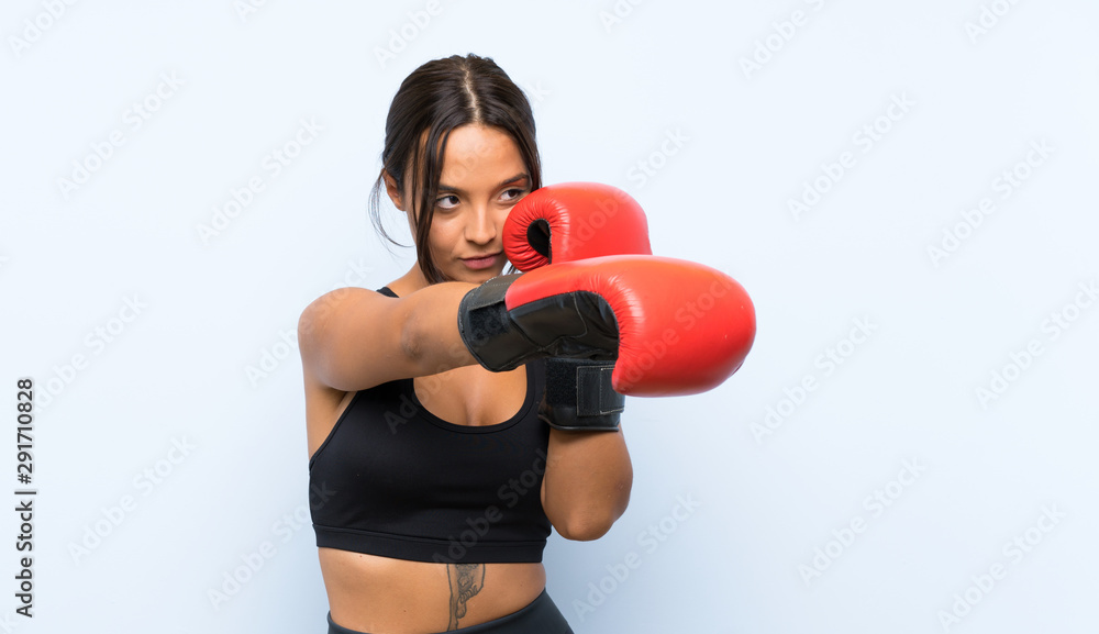 Young sport girl with boxing gloves over isolated blue background Young sport girl with boxing gloves over isolated blue background