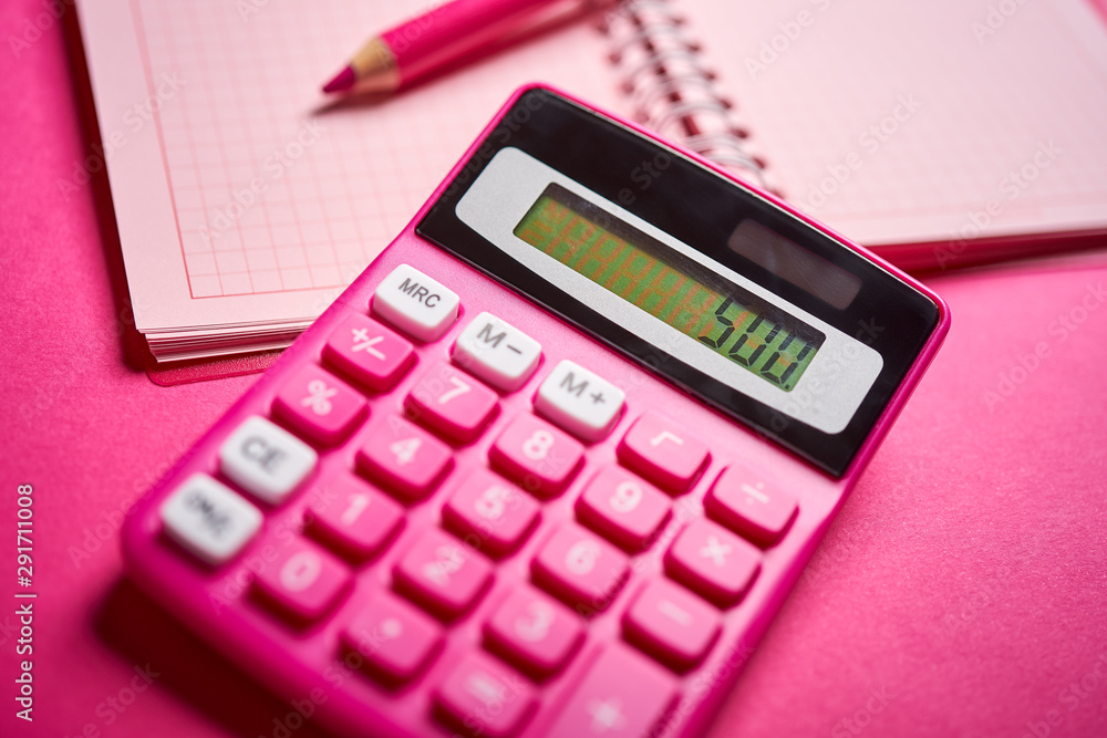 Closeup of calculator and notebook with pencil on pink desk Closeup of calculator and notebook with pencil on pink desk