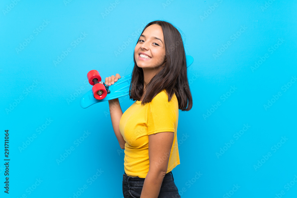 Young skater woman over isolated blue background Young skater woman over isolated blue background