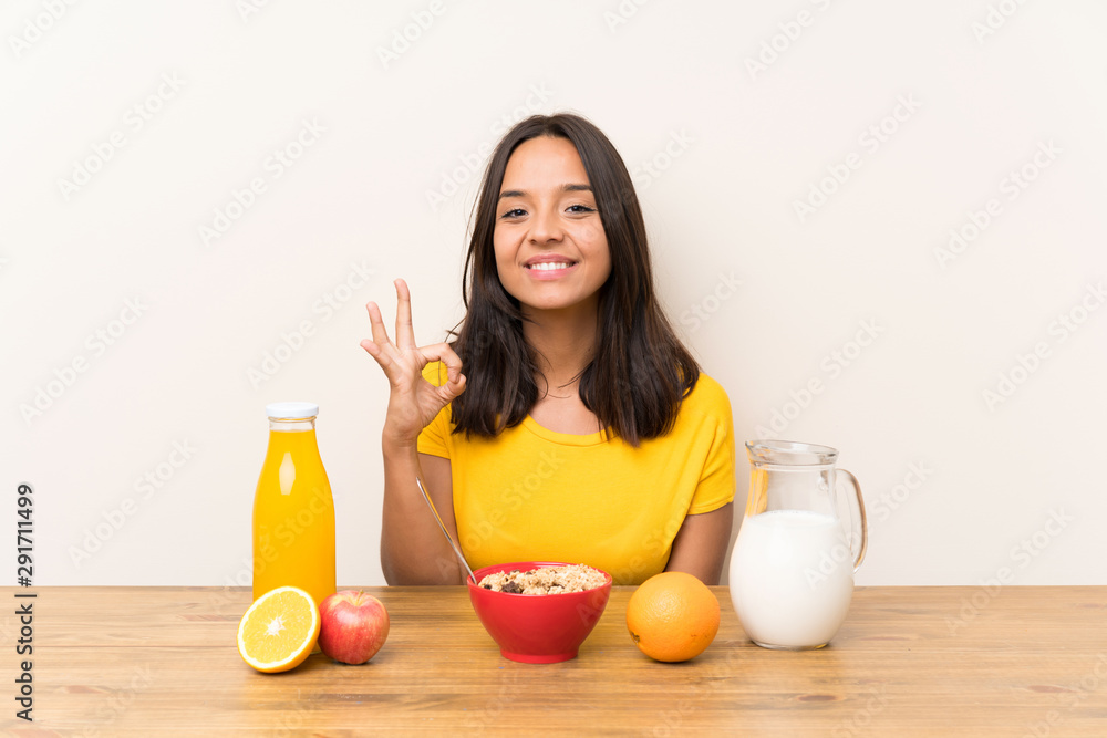 Young brunette girl having breakfast milk showing an ok sign with fingers Young brunette girl having breakfast milk showing an ok sign with fingers