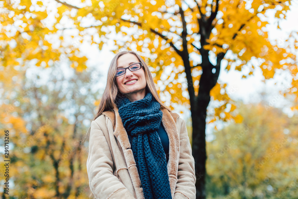 Woman standing on front of an autumn tree with colorful leaves Woman standing on front of an autumn tree with colorful leaves