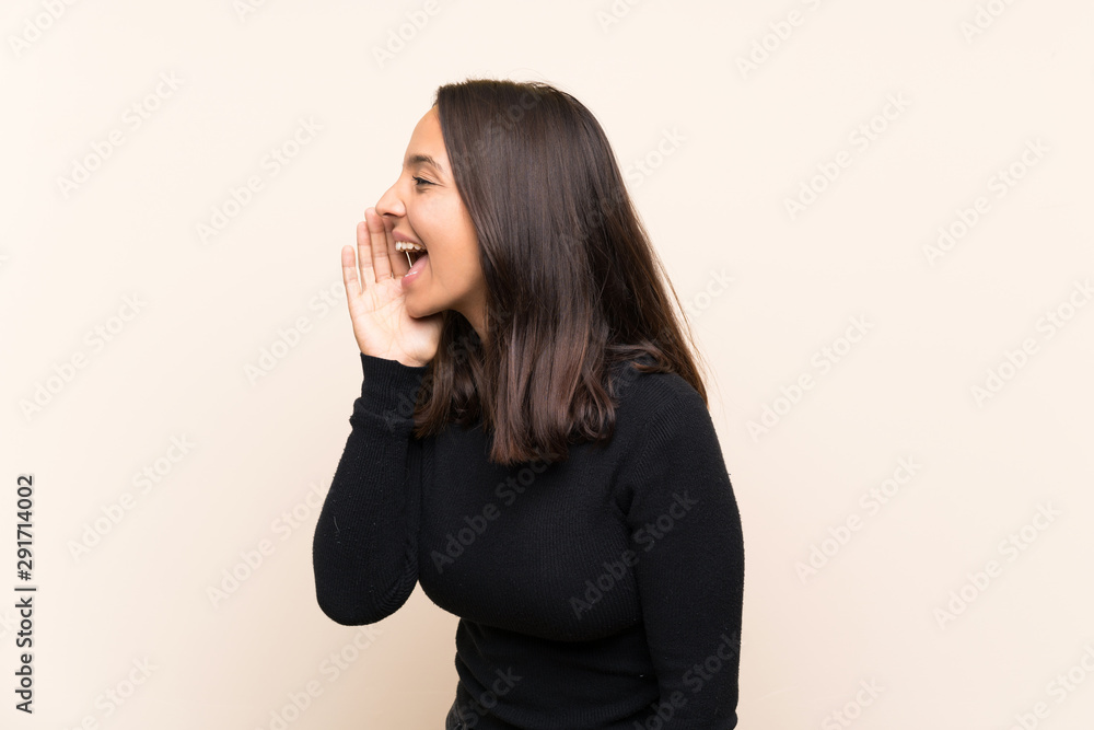 Young brunette woman with white sweater over isolated background shouting with mouth wide open to the lateral Young brunette woman with white sweater over isolated background shouting with mouth wide open to the lateral