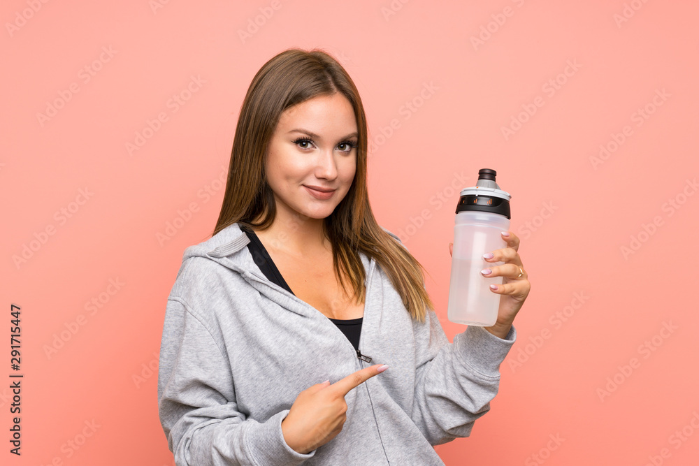Teenager sport girl with a bottle of water over isolated pink background Teenager sport girl with a bottle of water over isolated pink background