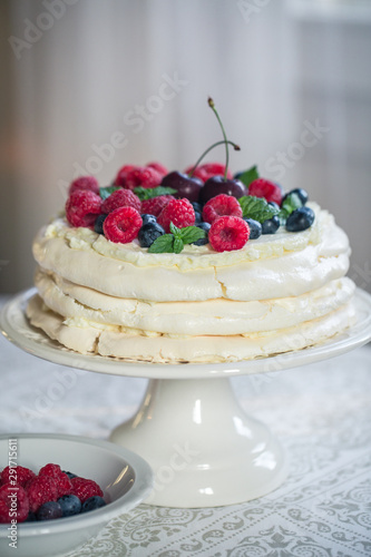 Homemade Pavlova cake with berries on the table in home interior.