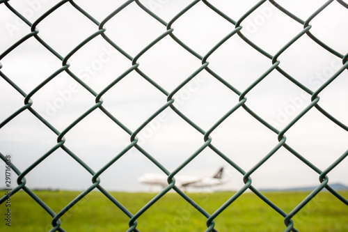 Metal fence with blurred out airplane landing in background