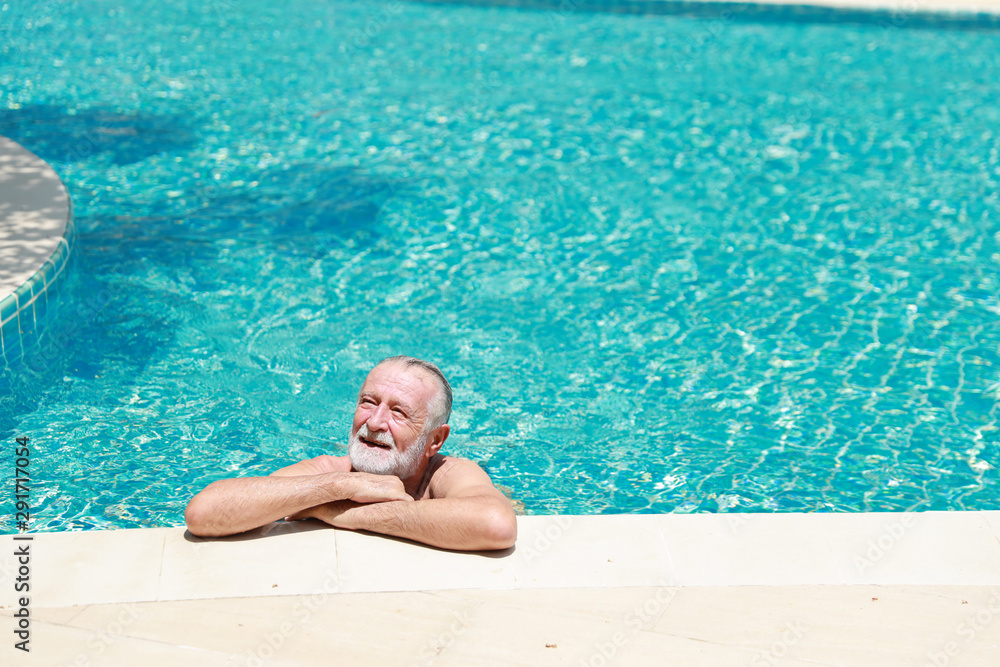 happy elderly caucasian swimming in pool during retirement holiday with relaxation and smiling