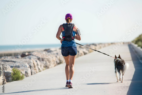 Photos young athletic woman doing canicross on the dike