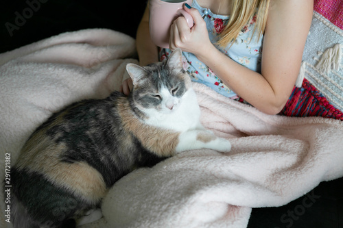 Girl cuddle with her cat while drinking coffee, sitting on couch, cozy