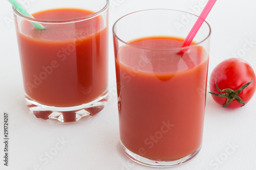 Two glasses of tomato juice on a white background