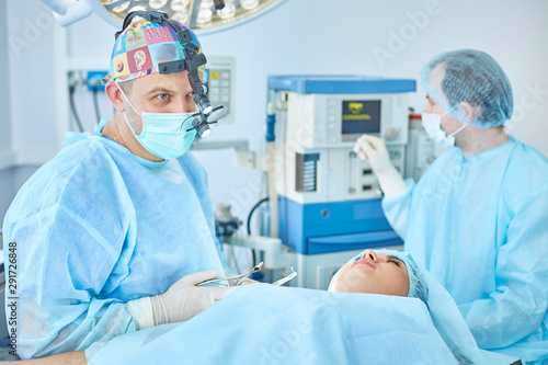 Several doctors surrounding patient on operation table during t