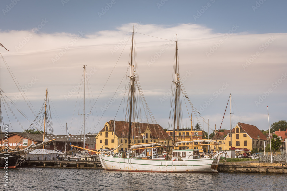 Old sailingboats in the port of Svendborg, at a jetty in front of two warehouses, Denmark, July 13, 2019
