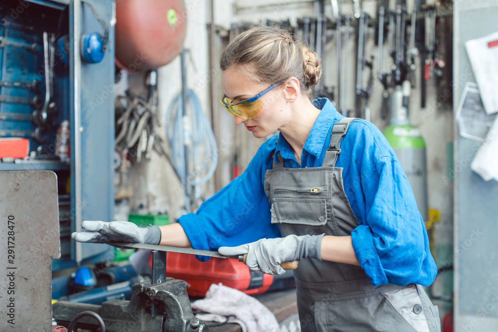 Woman worker in metal workshop deburring workpiece Woman worker in metal workshop deburring workpiece