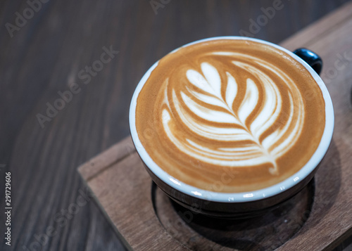 Fresh coffee latte art with heart shape tree milk pattern on top serve on wooden plate