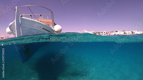 Above and below underwater photo of colourful fishing boat in turquoise clear Greek island sea