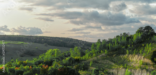 Aerial view of summer rural landscape with trees, grass, hills, dramatic sky and puffy clouds in evening. Russia, Samara.