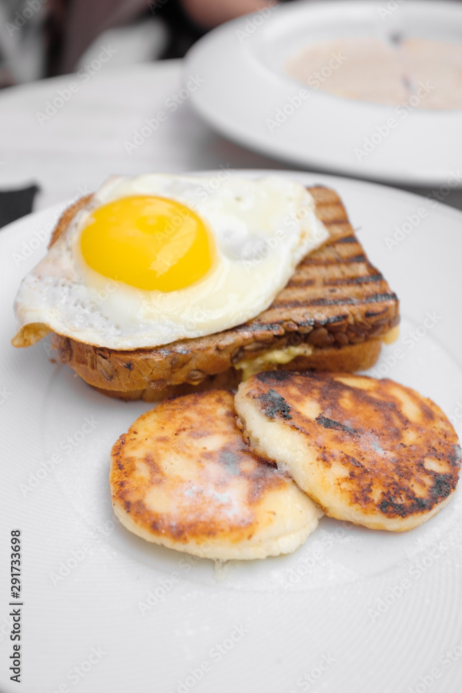 Tasty breakfast - toast, fried eggs, cheese pancakes on a white plate Tasty breakfast - toast, fried eggs, cheese pancakes on a white plate