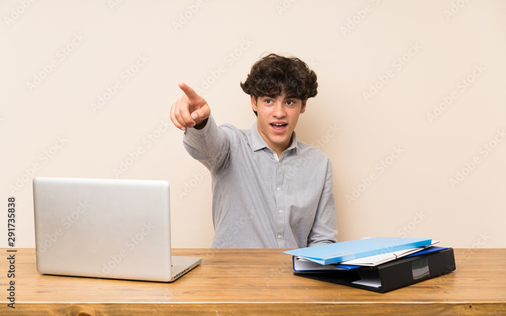 Young student man with a laptop pointing away Young student man with a laptop pointing away