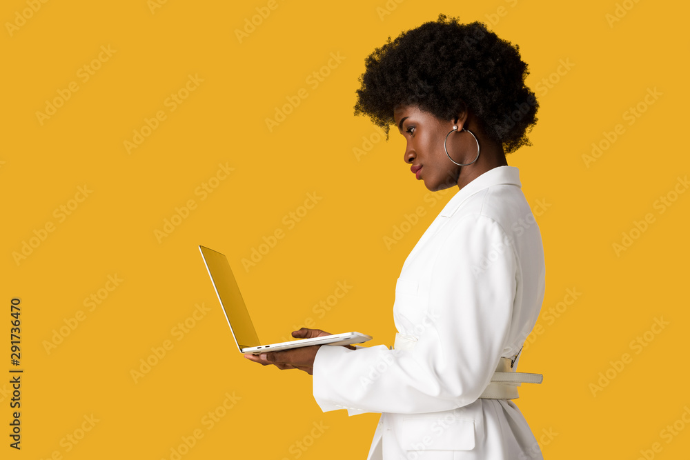 side view of african american girl using laptop isolated on orange side view of african american girl using laptop isolated on orange