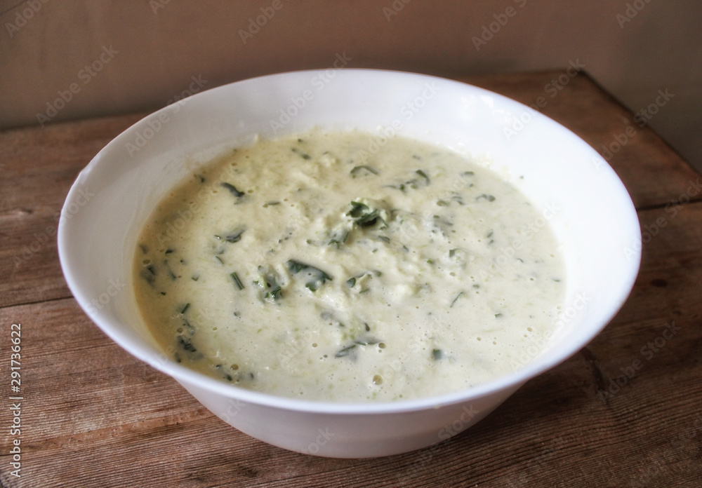 Dough for vegetable Zucchini pancakes with herbs in white bowl. Vegetable harvesting cooking concept Dough for vegetable Zucchini pancakes with herbs in white bowl. Vegetable harvesting cooking concept