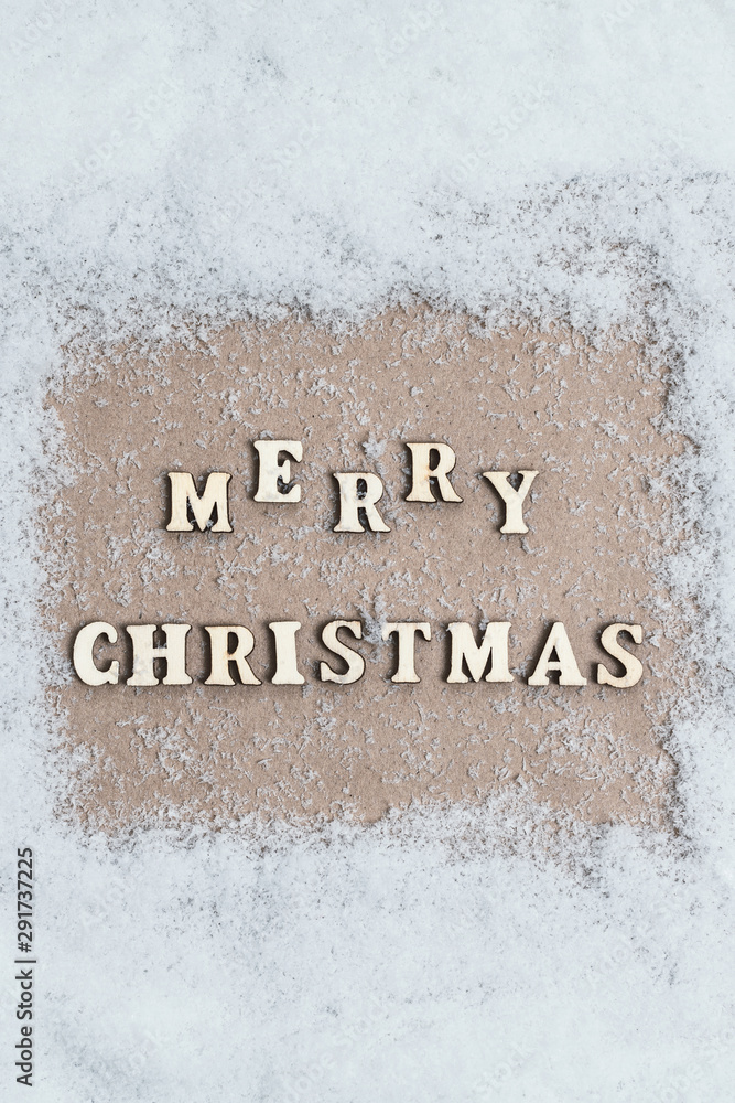 View from above. snow texture. craft paper in the middle with with the inscription merry christmas from wooden letters. Concept View from above. snow texture. craft paper in the middle with with the inscription merry christmas from wooden letters. Concept