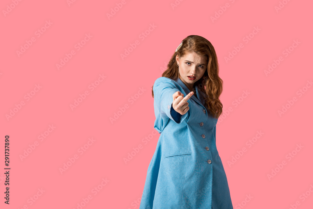 displeased redhead girl looking at camera and showing middle finger isolated on pink displeased redhead girl looking at camera and showing middle finger isolated on pink