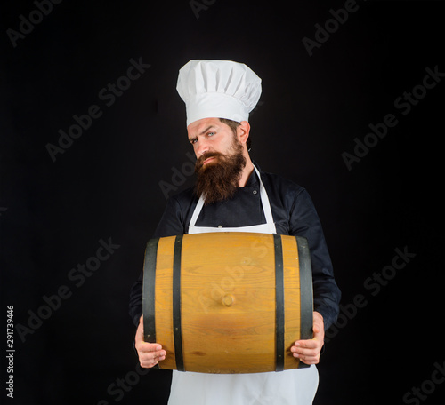 Bearded cook with wooden barrel of beer. Homemade wine. Wooden barrel of beer. Equipment for preparate of beer. Brewery for maturing alcohol. Celebration oktoberfest festival. Beer in Germany. Barman. photo