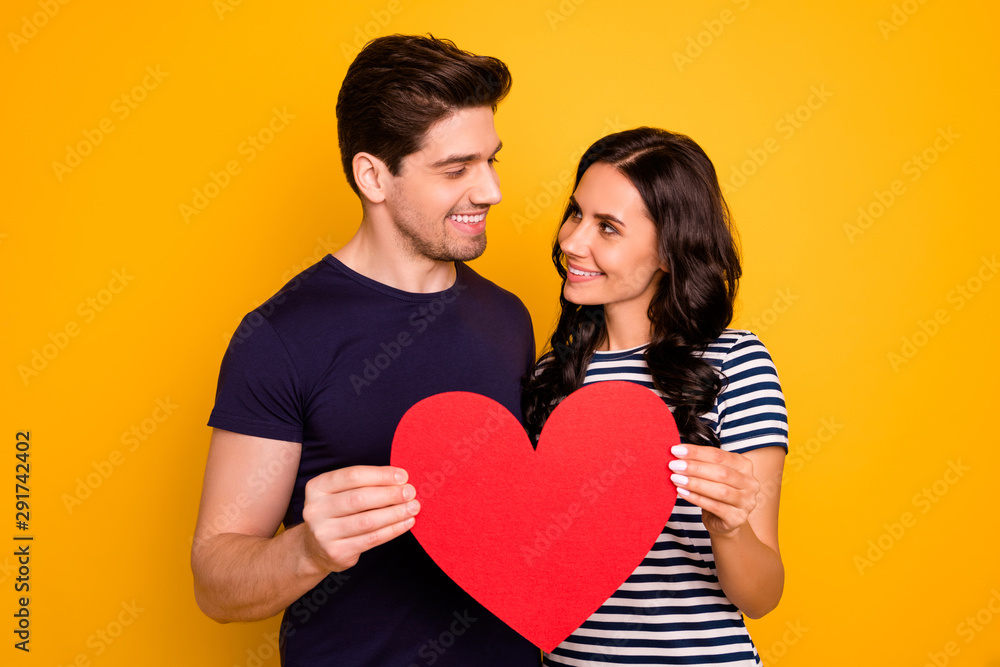 Photo of cheerful cool nice couple of handsome man and beautiful charming girl wearing striped t-shirt in love with each other isolated with yellow background