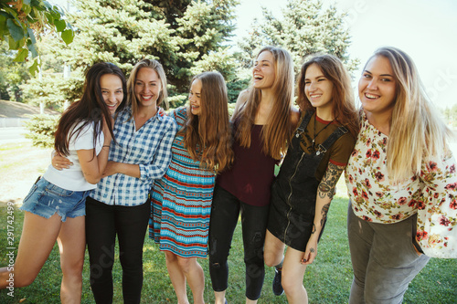 Different and happy in their bodies. Young women smiling, talking, walking and having fun together outdoors on sunny summer's day at park. Girl power, feminism, women's rights, friendship concept.