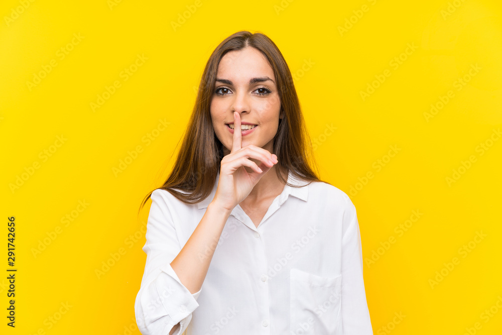 Young woman over isolated yellow background doing silence gesture Young woman over isolated yellow background doing silence gesture