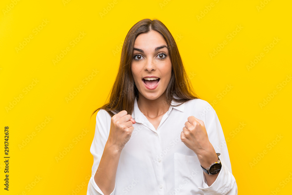Young woman over isolated yellow background celebrating a victory Young woman over isolated yellow background celebrating a victory