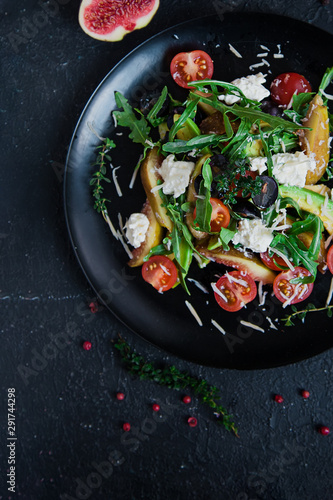salad on a plate: arugula, cherry tomatoes, white figs, grated cheese, black grapes
