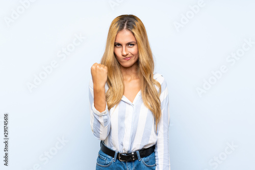 Young blonde woman over isolated blue background with angry gesture © luismolinero