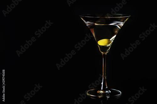 Martini glass and olives on a black background. Selective focus. Close up.