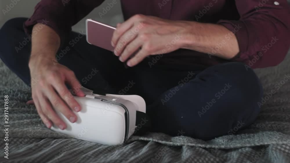 Man puts smartphone in VR glasses at home Man puts smartphone in VR glasses at home