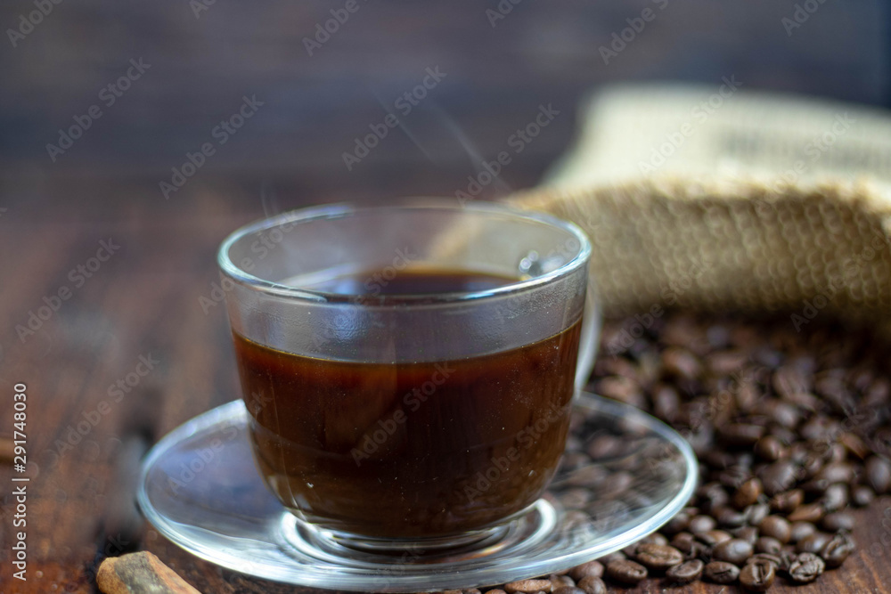 Coffee in a transparent cup. Hot, invigorating drink. Near cones in sparkles, coffee beans are scattered. Coffee in a transparent cup. Hot, invigorating drink. Near cones in sparkles, coffee beans are scattered.