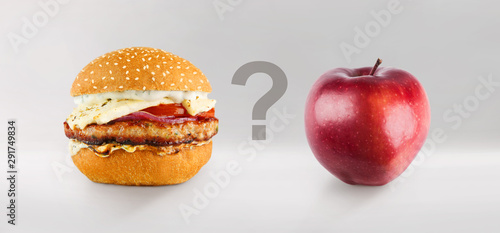 Burger and apple on gray background with question between