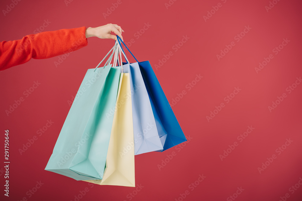 cropped view of woman holding shopping bags isolated on red