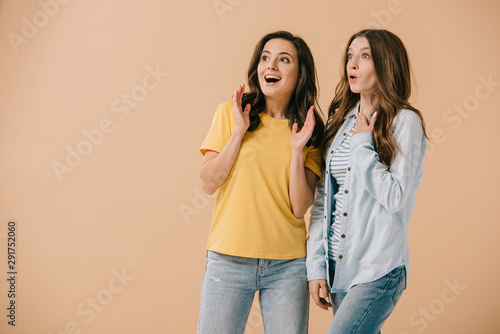 attractive and smiling friends looking away isolated on beige