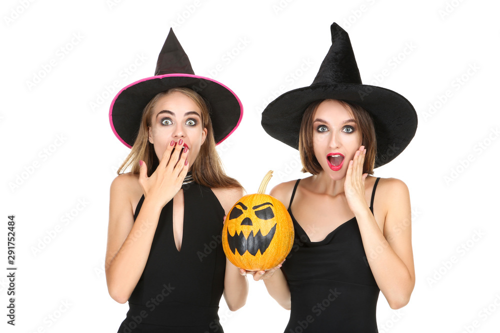 Two young women in black costumes with halloween pumpkin on white background Two young women in black costumes with halloween pumpkin on white background