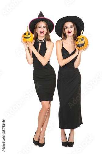 Two young women in black costumes holding halloween pumpkins on white background