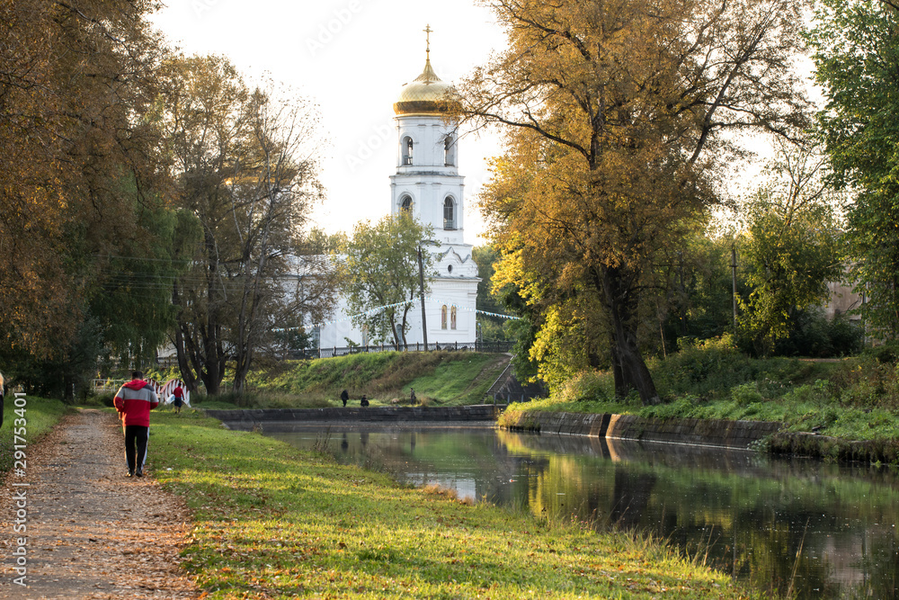 The pedestrian is directed towards the white building of the Epiphany Cathedral along the canal in the town of Vyshny Volochek Tver region Russia