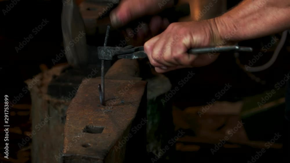 Blacksmith in forge beats hot metal on anvil with hammer. Smith beating hammer hot iron on anvil in forge. Blacksmithing concept. Blacksmith in forge beats hot metal on anvil with hammer. Smith beating hammer hot iron on anvil in forge. Blacksmithing concept.