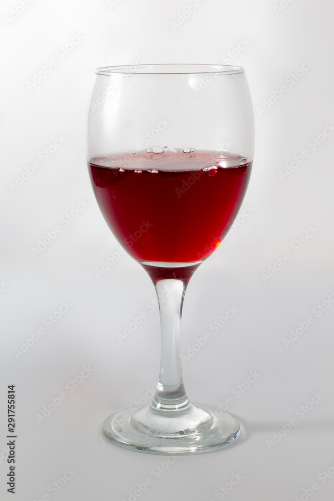 A cup glass of red wine on with a shadow on the right side. A cup glass of red wine on with a shadow on the right side.
