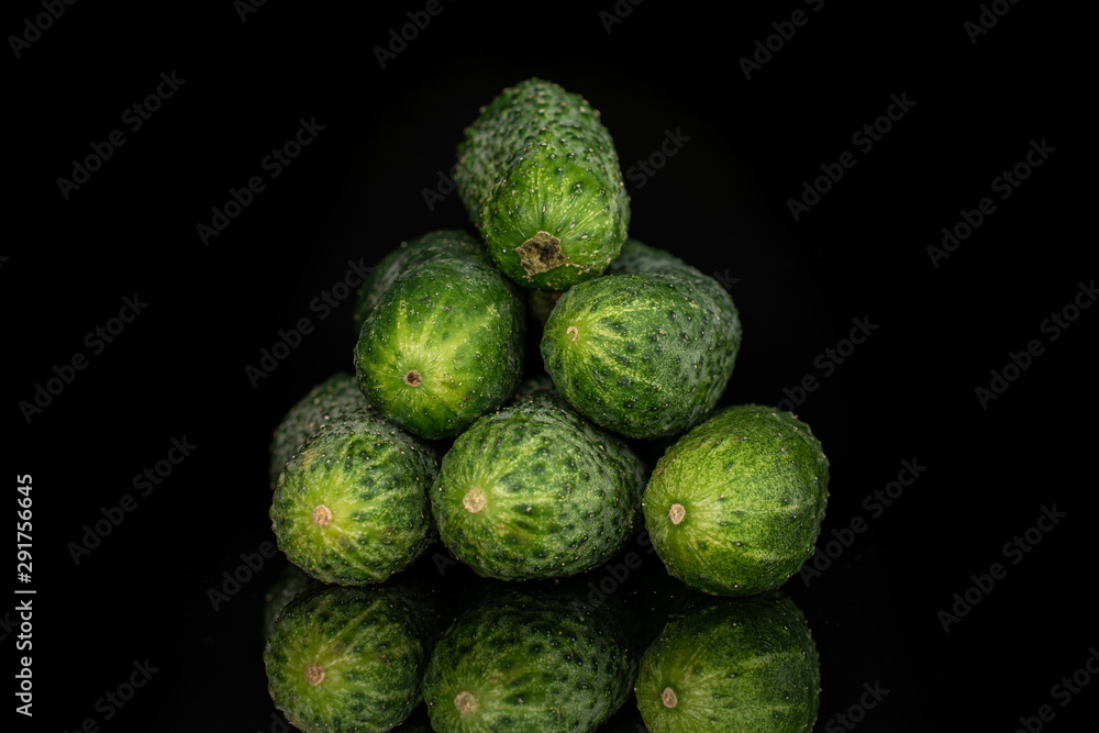 Obraz premium Group of six whole fresh pickling cucumber pyramid isolated on black glass