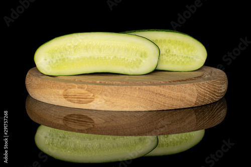 Group of two halves of fresh green pickling cucumber section on bamboo plate isolated on black glass photo