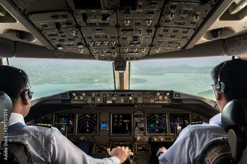 Inside cockpit of commercial airplane while fly approaching the runway. Outside window can see beautiful light from airport and inside cockpit can see pilots flying airplane. Modern aviation concept. photo