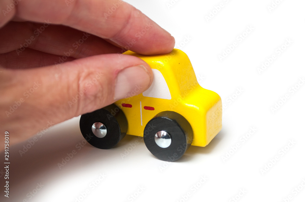 closeup of miniature wooden car in hand on white background closeup of miniature wooden car in hand on white background