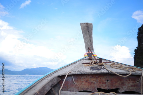 A wooden boat in the middle of the ocean There is an anchor on the boat and big cloud