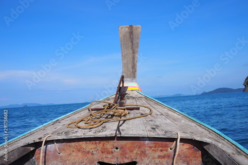 A wooden boat in the middle of the ocean There is an anchor on the boat.